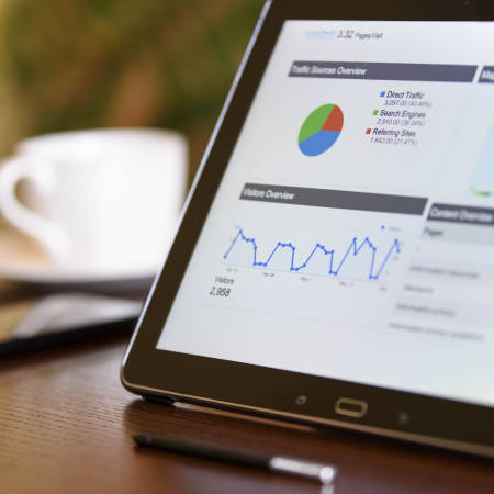 Charts and analytical data on the tablet screen with a cup of coffee and a telephone in the background